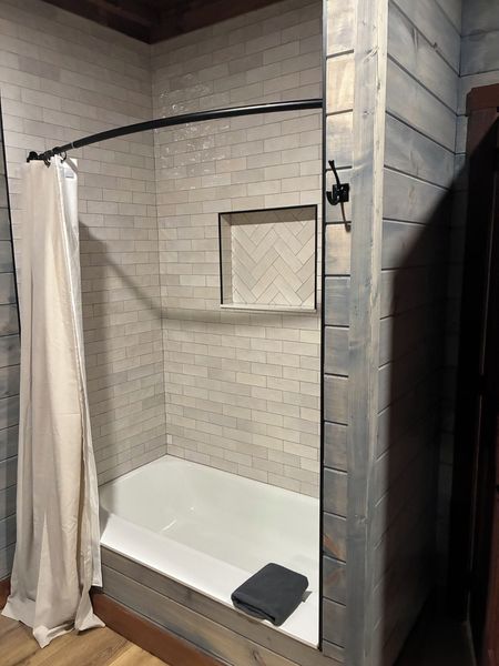 Tiled tub and shower combo with a curved rod and a recessed niche