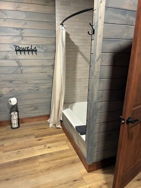 Tub and shower combo seen from the bathroom doorway, with a Towels hook rack