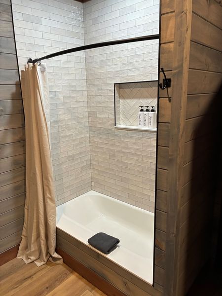 Tub and shower combo with white subway-style tile and a niche with toiletries