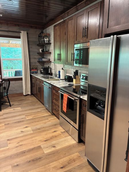 Galley kitchen with dark wood cabinets, a stainless refrigerator, range, and microwave