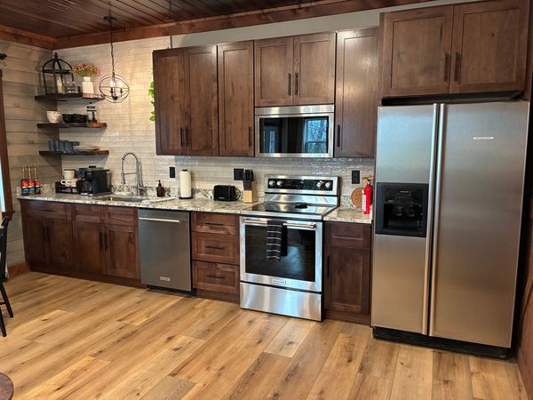 Full kitchen with dark wood cabinets, a stainless refrigerator, range, microwave, and dishwasher