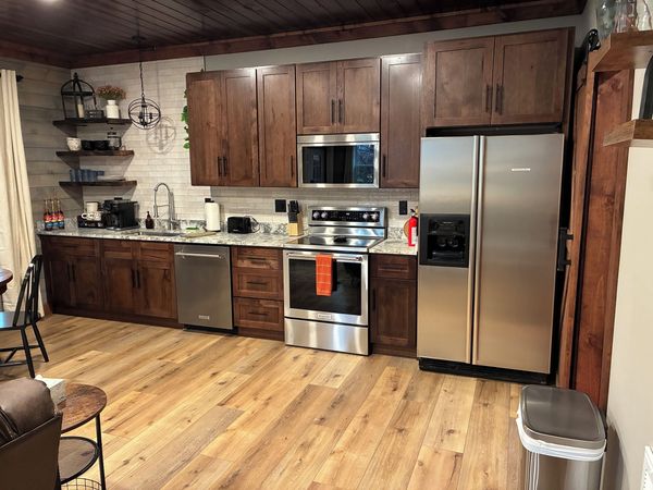 Barnhouse kitchen with dark wood cabinets, open shelving, a stainless refrigerator, range, and dishwasher