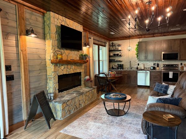 Stone fireplace with a TV, looking toward the kitchen, with a leather sofa in front
