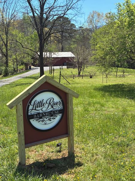 Little River Barnhouse sign on the lawn, with the red barn in the background