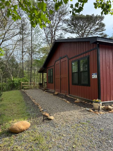 Side of the red Barnhouse with black-framed windows and a gravel path