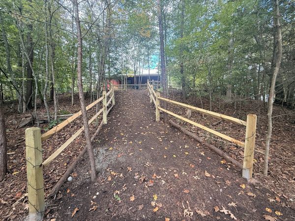 Path between split-rail fences leading through the woods back to the Barnhouse