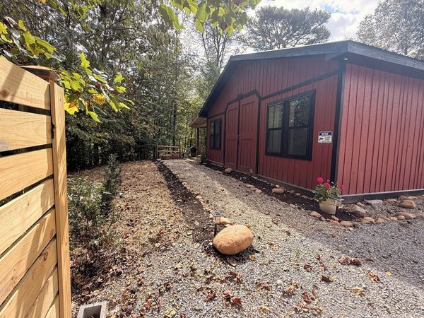 Gravel path along the side of the red Barnhouse beside a wooden privacy fence