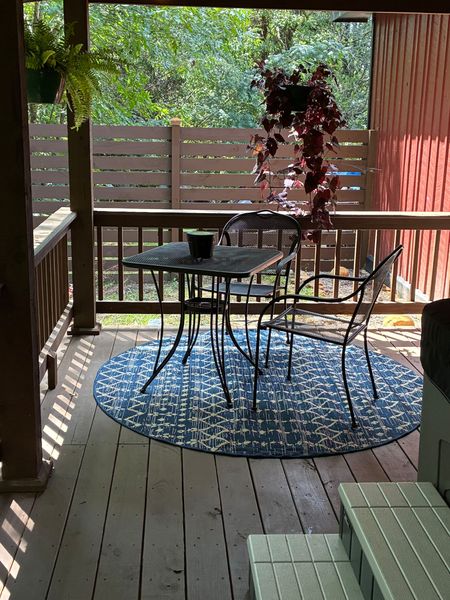 Bistro table and chairs on a rug at the end of the covered porch