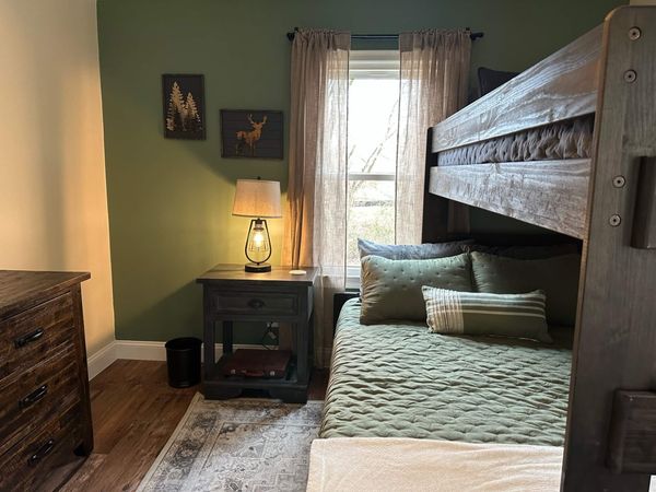 Bunk room with a dark wood bunk bed, bedding, and a nightstand with a lamp