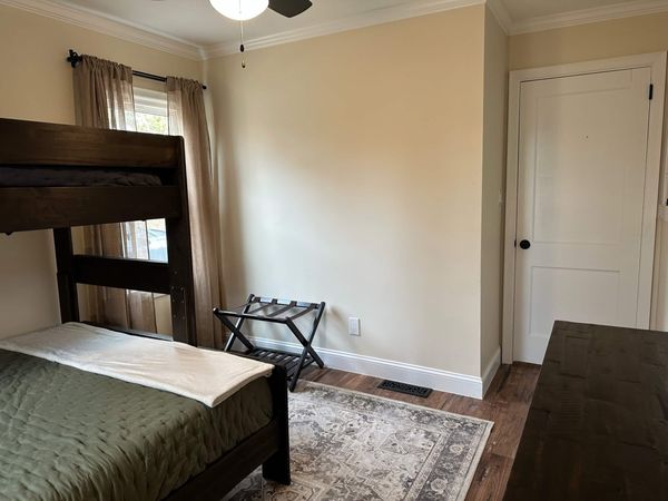 Bunk bed with bedding, a folding luggage rack, and a patterned rug