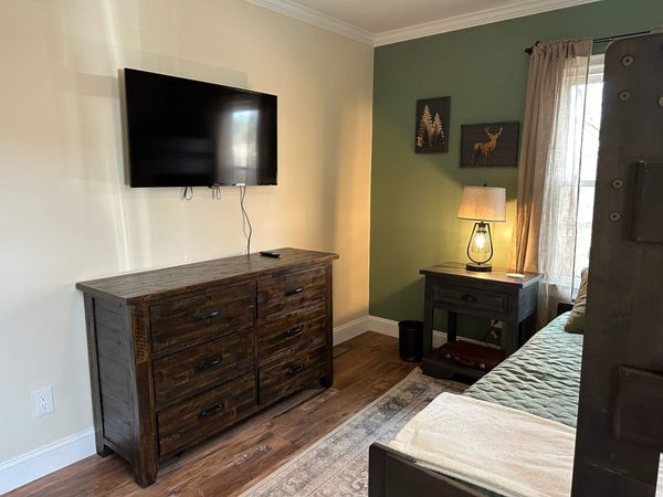 Bunk room dresser with a wall-mounted TV, and a nightstand by the window