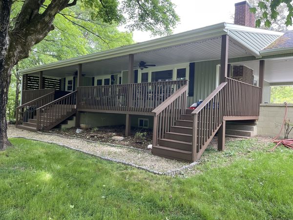 The Farmhouse's long covered deck and two staircases, seen from the yard