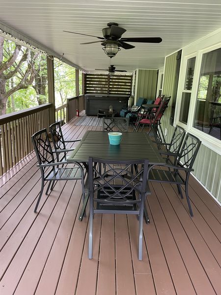 Outdoor dining table and chairs on the long covered deck under ceiling fans