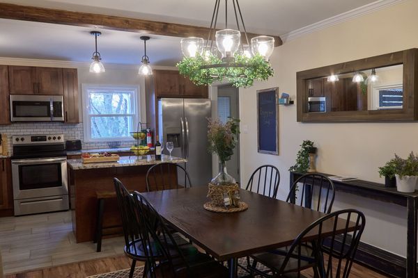Dining table and chandelier looking toward the kitchen's stainless range and refrigerator