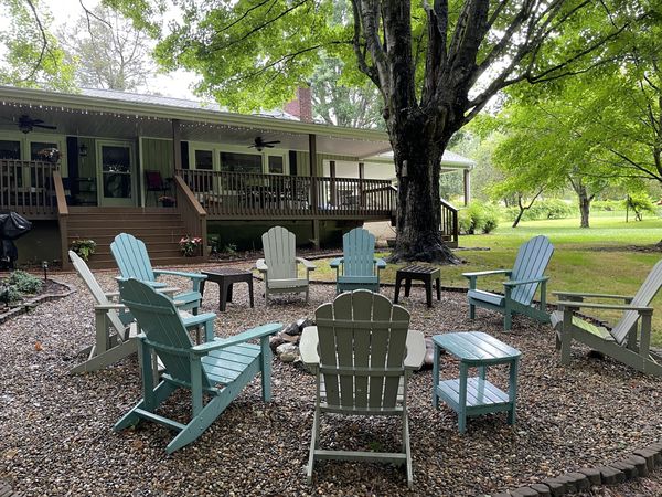Fire pit circle with Adirondack chairs on gravel in front of the Farmhouse back deck
