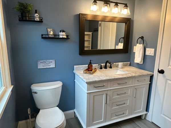 Guest bathroom with a vanity, dark wood mirror, and toilet