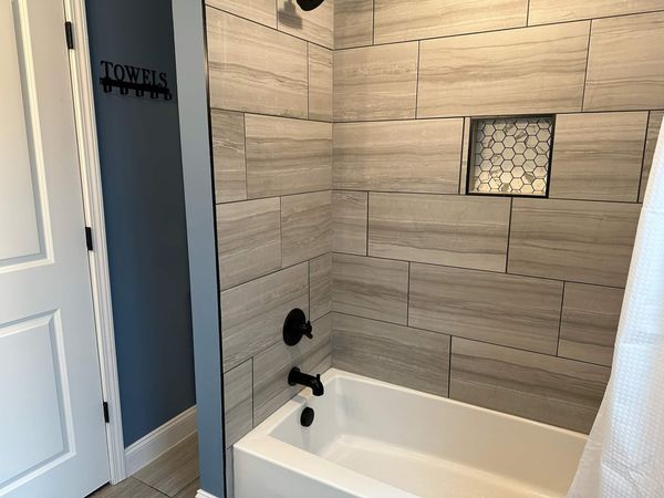 Guest bathroom tub and shower combo with plank tile and a hexagon-tile niche