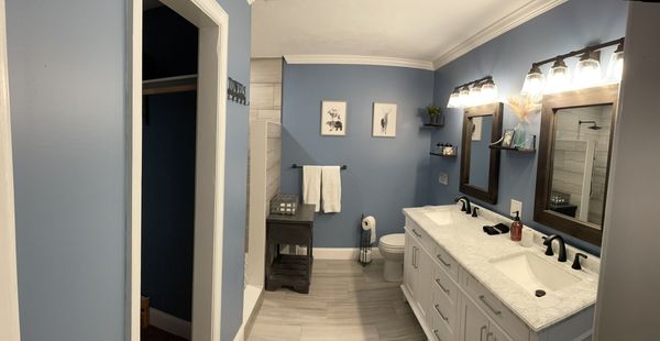 Master bathroom with a long double vanity, dark framed mirrors, and painted walls