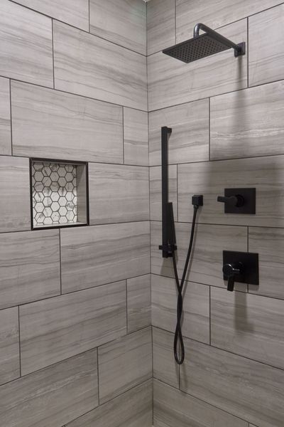 Tiled shower with a rainfall shower head, handheld sprayer, and hexagon-tile niche