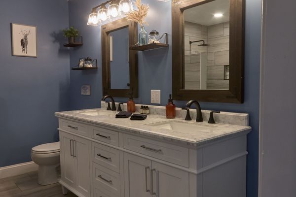 Master bath white double vanity with a marble-look top and two dark wood mirrors