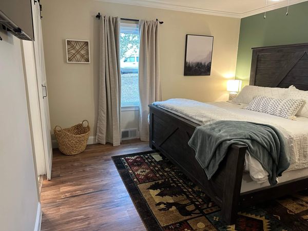 Master bedroom with a king bed, dark wood headboard, accent wall, and patterned rug