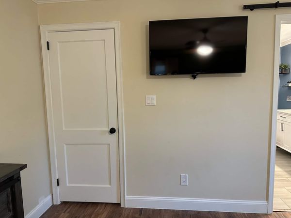 Wall-mounted TV in the master bedroom beside the door