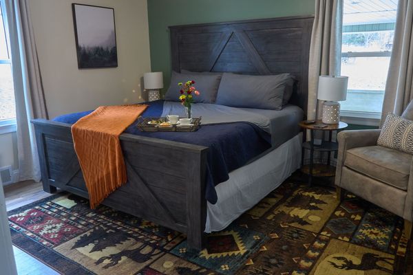 King bed with a wood headboard, bedding, a throw, and a breakfast tray with flowers