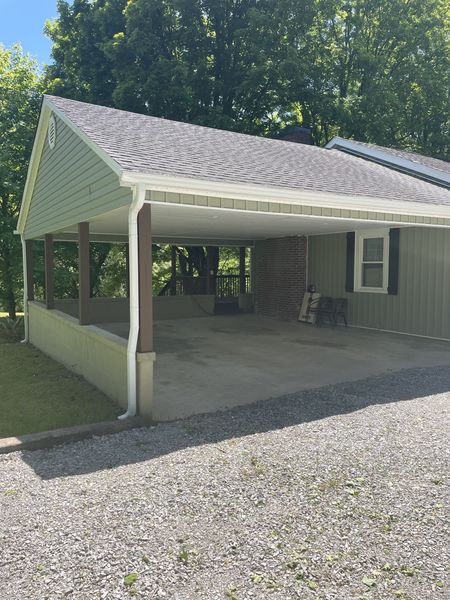 Covered carport attached to the Farmhouse beside the gravel drive