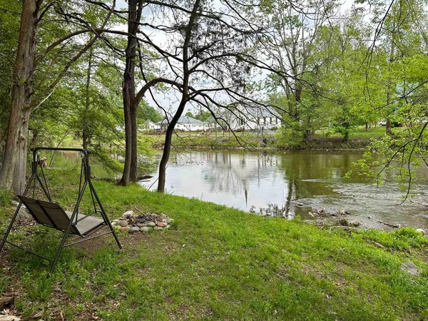 Wooden porch swing on a grassy bank above Little River