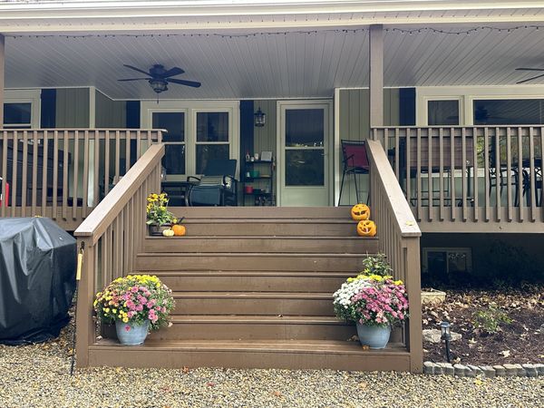Deck steps decorated with pumpkins and potted mums in front of the covered deck